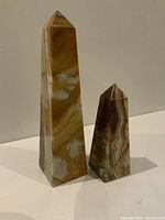 Two polished onyx obelisk towers, tall and short, showing natural veining and multi-colored stone patterns