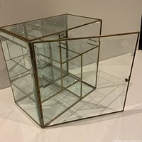 Curio cabinet with door open, showing interior compartments and brass framework