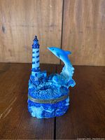 Front view of the dolphin themed trinket box showing dolphin jumping over waves and lighthouse