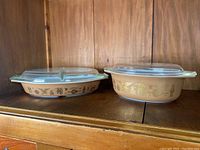 Side view of both Early American Pyrex casseroles on wooden shelf, showing pattern and glass lids