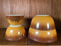 Four vintage Pyrex mixing bowls stacked with the smallest bowl showing the Old Orchard pattern on the outside.