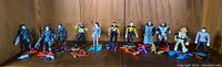 Wide shot of all 12 Star Trek action figures arranged in a line showing colors, outfits, and accessories.