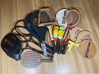 Full assortment of vintage rackets, paddles, tennis balls in cans, and vintage Lark bag visible
