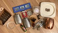 Full view of lot contents with barware, collectibles, and memorabilia items arranged on wooden floor.