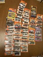 Overview photo showing all 40 Matchbox vehicles still sealed in original blister packs with orange and blue packaging, displayed on a wooden surface.