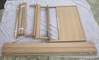 Disassembled components of the William Sonoma Inc. twin bed frame laid out on a white sheet, showing side rails, headboard/footboard panels, slat supports, and braces in light birch wood.