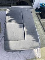 Top view of the grey microvelvet loveseat with ottomans arranged flat outdoors on a towel.