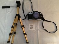 Camera alongside tripod stand showing overall appearance and size comparison