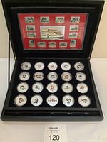 Full open display case showing stamp sheet on lid and tray of 25 mascot coins
