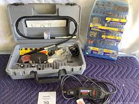 Full view of the Dremel MultiPro rotary tool kit in open gray carrying case, showing flexible shaft, accessories and sanding discs inside case and additional accessory packs to the right.