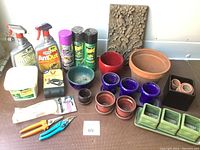 Full lot view including flower pots, pest control sprays, garden tools, and stone plaque