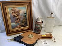 Full lot view showing beer stein, glass bottle, framed oil painting, and wooden bellows.