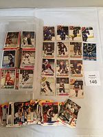 Top view of the assortment of hockey cards laid out on a white surface plus a plastic container labeled 'hockey' containing more cards