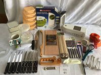 Photo showing entire lot of kitchen gadgets, including Starfrit salad spinner box, knives, containers, skewers, cutting boards, and various tools.