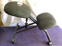Side angle of kneeling chair showing two padded cushions and black metal frame with wheels