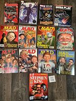 Photo of a collection of assorted magazines including MAD Magazines with various themes, Marvel Previews comics, and a Stephen King special edition magazine.