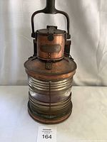 Front view of the vintage copper and brass masthead lantern with glass lens and carry handle.