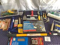 Full view of all tools laid out - paint scrapers, glue gun kit, paint roller extension pole, and assorted accessories