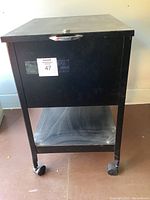 Front view of black metal rolling filing cabinet with lock and caster wheels
