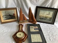Photo showing entire lot with two framed pictures, two mahogany sailboats, wall barometer, and framed timetable.