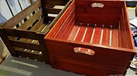 Photo showing both the red and brown wooden crates side by side on a carpeted floor.