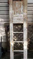 Photo of full antique wooden door showing chipped paint and ladder-like bottom half