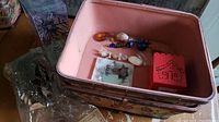 Overview of lot contents inside a pink metal basket showing red tea light holder, ornaments, and packaged items.