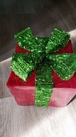 Top view of red box with large green glitter ribbon and bow on top