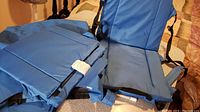 Image showing two light blue padded foldable seats, one open and one folded to backpack shape with straps