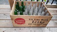 Overview of the wooden Lantic Sugar crate containing various green and clear vintage soda bottles organized in rows