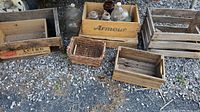 Six wooden crates including one with Atlantic Sugar branding, one with Armour label containing bottles, and one labeled Bright's Wines Limited, alongside a small wicker basket and several glass bottles arranged on gravel.