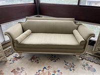 Front view of a champagne-colored curled arm couch with clawed bronze feet on a floral rug, showing overall style and condition.