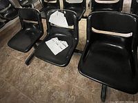 Front view showing three black plastic molded seats with backrests mounted on a metal frame, seating length around 6 feet.