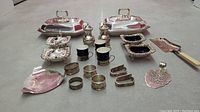Wide angle view of the collection showing all silver plated and glass items including two large lidded platters, napkin rings, salt and pepper shakers, servers, and cake server.