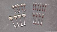 Photo showing the entire set of 18 silver plated cutlery pieces laid out on a surface, including teaspoons, forks, and tablespoons.