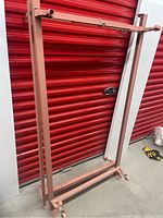 Full view of one pink metal bed frame with caster wheels, showing rectangular structure and pink paint.