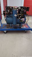 Front view of Wilkerson 2 HP oil lubricated air compressor showing blue tank and vertical oil reservoir with piping and compressor heads on top.
