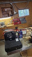 Motomaster battery charger, automotive fluid, and closed socket set case on a metal table in a workshop