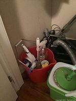 Photo of red pail containing spray bottles, cleaning brushes, lint roller, and containers of cleaning solutions