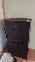 Front view of solid wood five drawer dresser showing dark finish, matching handles, and some paint chips.