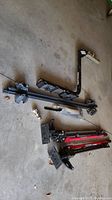 Photo shows black metal SportRack bicycle carrier hitch, GM roof racks, ball hitch, and two red and black Power Fist 36-inch 2 tonne farm jacks arranged on a concrete floor.