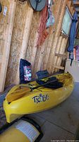 Yellow kayak on black cradle showing full side profile and “Tribe” logo