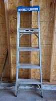 Front view of the Lite aluminum folding step ladder showing all four steps and blue plastic top tool tray.