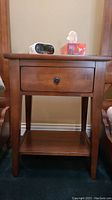 Front view of solid wood night stand showing drawer with metal knob and tapered legs.