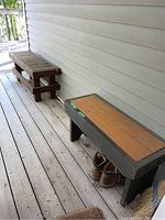 Image showing two wooden benches on front porch, one with natural wood top and dark painted frame, the other with a slatted design