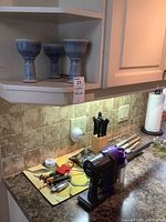 Photo showing Dyson DC34 Animal handheld vacuum in purple and gray with charger and knife set on kitchen counter.