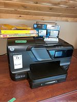 Front view of HP OfficeJet Pro 8600 printer with ink cartridges and photo paper on top.
