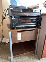Sony 5 CD changer on top of Sony receiver sitting on wood cabinet