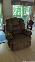 Front view of large brown fabric recliner chair with arm covers and cushioned segmented backrest.