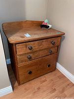 Front view of wooden wash stand showing three drawers with wooden knob pulls and signs of wear.